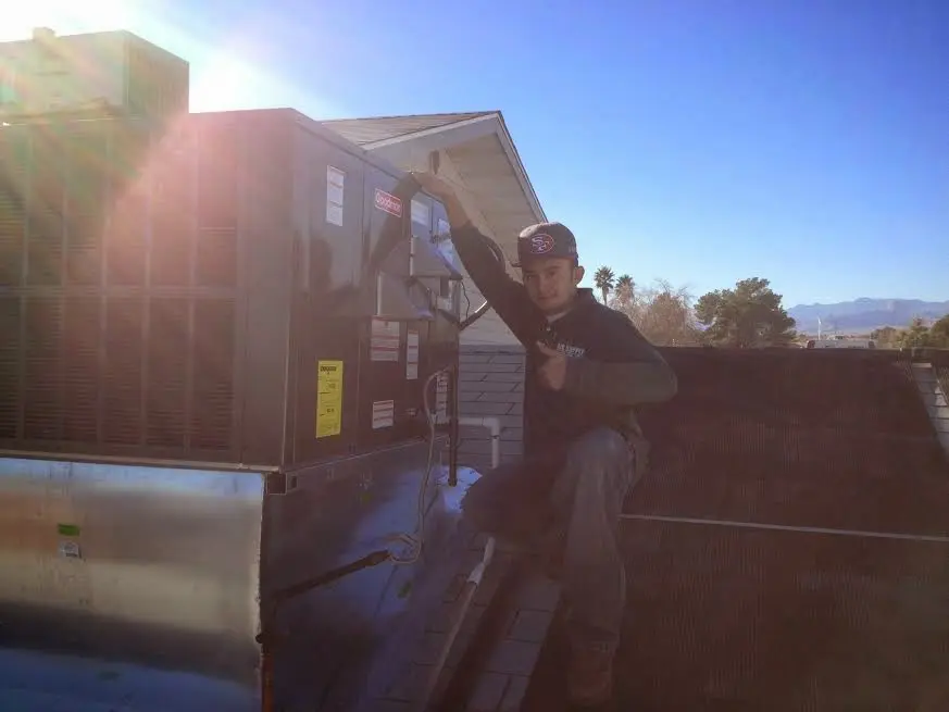 HVAC technician performing Air Duct Cleaning on a rooftop unit in Silvis